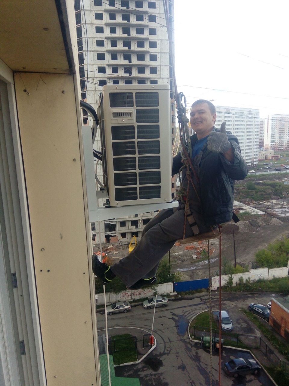 Мастер выполняет высотный монтаж наружного блока кондиционера